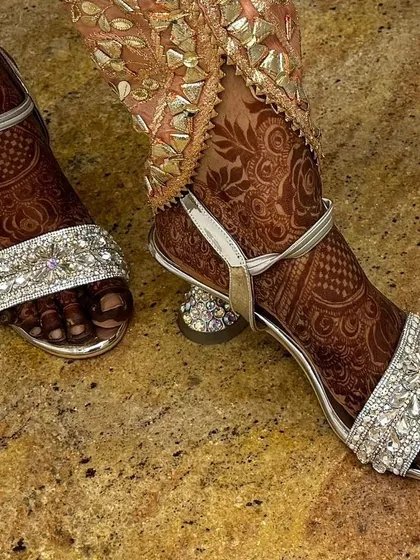 The beautiful henna stain on the bride's feet, perfectly complementing her elegant bridal footwear.