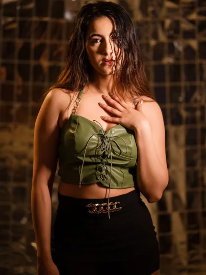 A powerful, direct-to-camera look. The combination of the unique background, styling, and moody lighting makes this a standout shot.