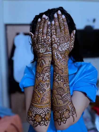 A playful peek-a-boo pose from the bride, showing off her unique henna with personalized names.