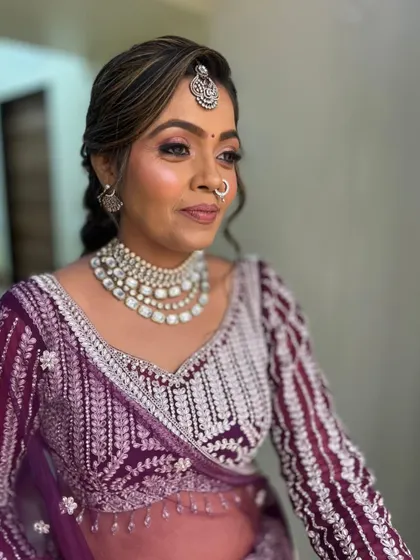 A close-up of a client in a deep purple lehenga with intricate silver embroidery.