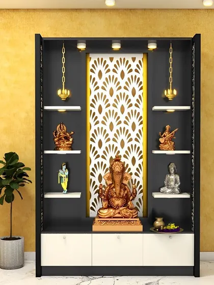 A modern pooja unit in black and white, with a beautiful laser-cut panel in a peacock feather pattern. The hanging brass lamps add a traditional touch.
