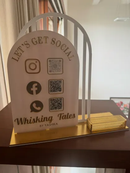 A full view of the 'Whisking Tales' social media stand, designed to hold business cards and display multiple QR codes in a sophisticated style.