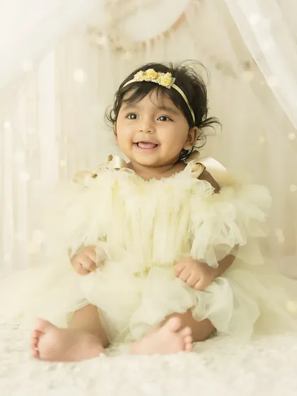 A perfect sitter session portrait. This 6-month-old is sitting up proudly, showing off her adorable smile and chubby feet.