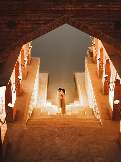A dramatic pre-wedding shot inside a stepwell, with the couple embracing on the stairs, beautifully lit from below.