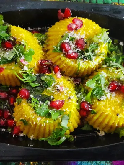 Bite-sized Nylon Khaman presented as savoury cupcakes. They are garnished with pomegranate, fresh coconut, and coriander.