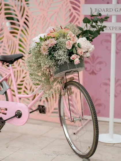 A pink bicycle with a basket overflowing with flowers serves as a charming and whimsical prop for a garden party.