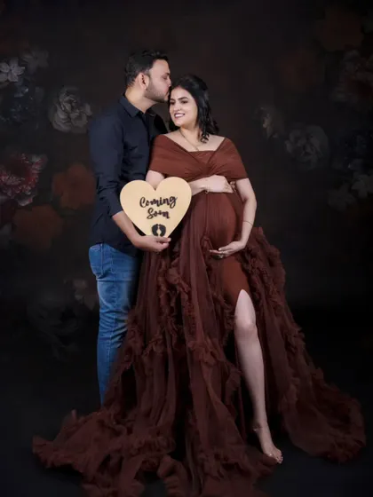 Announcing the big news with a sweet, heart-shaped "Coming Soon" sign. This is a classic couple's pose that is full of warmth and excitement.