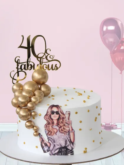 Celebrating "40 & Fabulous" with champagne and style. This chic cake features an edible print of a glamorous woman, accented with a cascade of edible gold spheres and a sparkling topper.