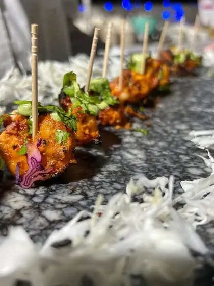 A close-up of our spicy paneer bites, neatly arranged on a marble platter. The contrast of the red paneer against the white shredded cabbage makes for a beautiful presentation.