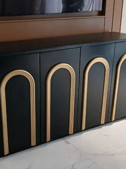 A close-up of the black and gold media cabinet, showing the clean lines and the elegant contrast between the matte black finish and the metallic arches.