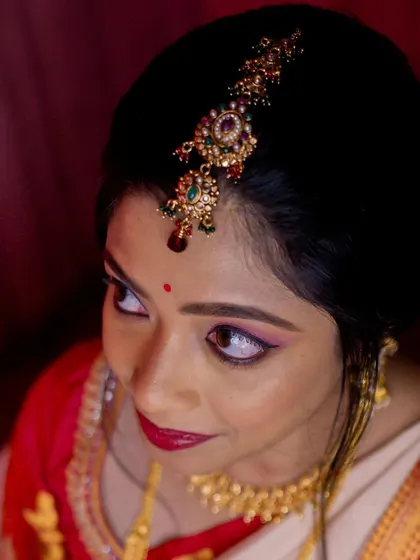 This top-down view highlights the beautiful hair accessory and the precise, winged eyeliner that defines the bride's eyes.