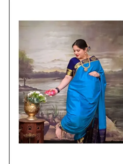Inspired by the grace of figures in Raja Varma's paintings, this pose captures the mother-to-be in a traditional blue saree. The painted landscape backdrop and antique brass vase add to the artistic, heritage feel of this unique maternity portrait.