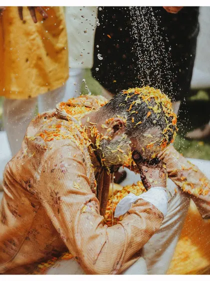 An intense candid moment as the groom is doused with water and haldi during the ceremony.