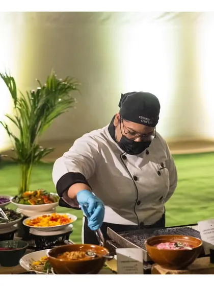 One of our female chefs preparing a dish at a live station, demonstrating the skill and dedication of our diverse team.