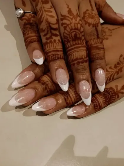 A classic and timeless choice for any bride. This is a perfectly executed French manicure with a sparkling base on long, almond-shaped nails, shown with bridal henna.