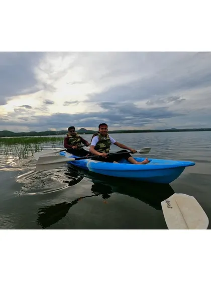 A candid shot of two friends smiling and paddling on the lake, capturing the simple joys of being outdoors.