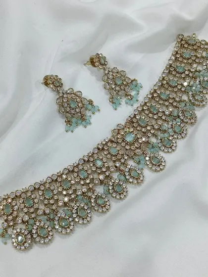 A beautiful choker set with pastel blue stones and a gold finish. This piece is perfect for pairing with modern lehengas or sarees for a subtle, elegant look.