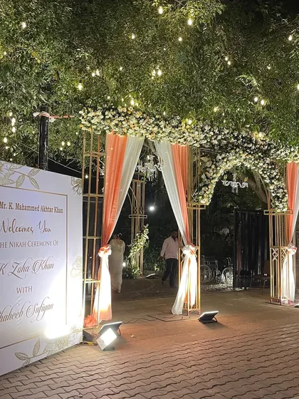 A grand and welcoming entrance to a Nikah ceremony, adorned with white and peach flowers and drapery. This sets a beautiful tone for the blessed union of the couple.