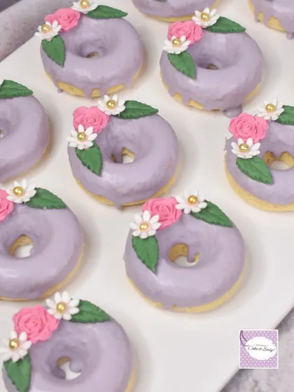 Baked donuts with a lavender glaze and delicate floral decorations for the fairy garden theme.