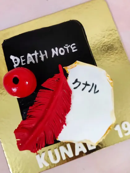 A cake inspired by the anime Death Note. I loved creating the iconic notebook, feather, and apple details for this unique birthday theme.