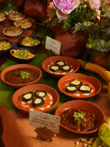 A spread of our modern Indian main courses served in traditional clay bowls. This includes our Palak Paneer Kofta with Makhani Gravy, showcasing our ability to cater full meals with authentic presentation.