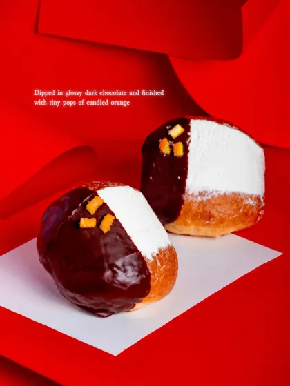 The Maritozzo is dipped in glossy dark chocolate and finished with tiny pops of candied orange.