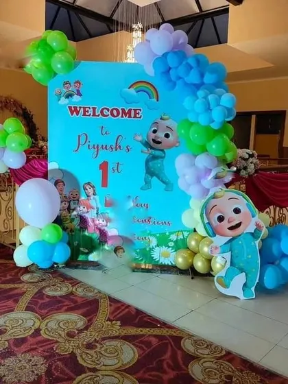 A Cocomelon themed welcome setup for a first birthday party, featuring a custom backdrop and character cutout.