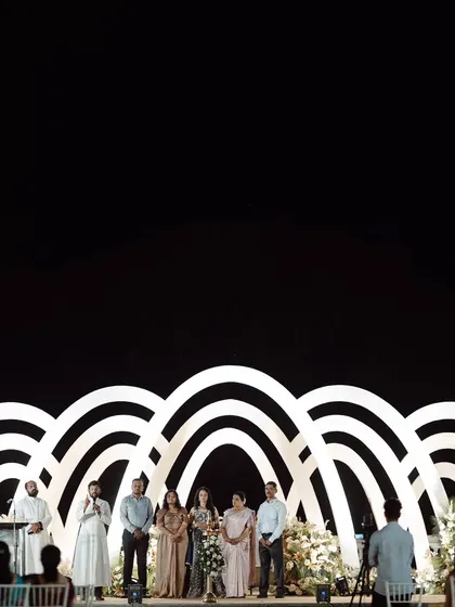 A wide shot of the spectacular stage for a Roce ceremony. The series of illuminated white arches creates a powerful architectural statement against the night sky.
