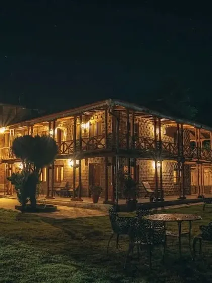 The Chevron Eco Lodge at night. The warm lighting from the balconies and windows creates a stunning and inviting view against the dark sky.