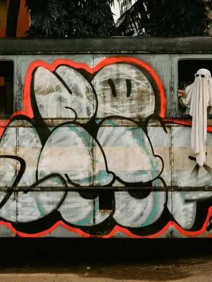 A wide shot of the ghost couple against a graffiti-covered bus, creating a cool, urban-spooky vibe.