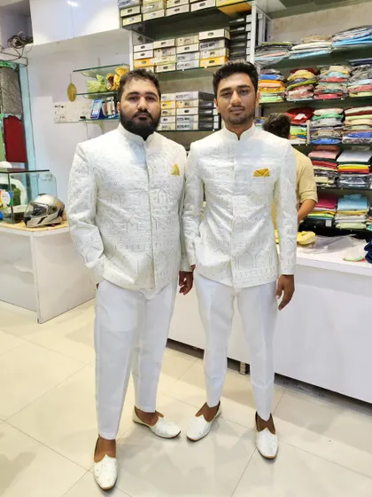 The two clients in their matching white Jodhpuri suits, smiling and ready for the event.