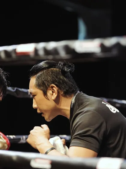 A close-up of Coach Netra, focused and dedicated, guiding a fighter between rounds.