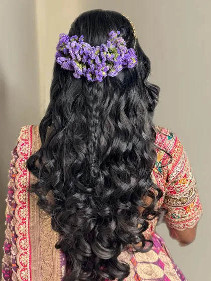 A closer look at the beautiful mehendi hairstyle. We created voluminous curls with braids and adorned them with fresh purple flowers for a romantic touch.