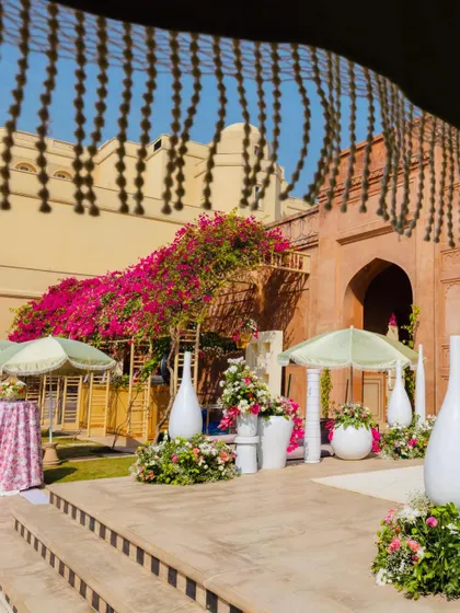 The view from the steps, showcasing the beautiful contrast between the historic fort architecture and our fresh, modern decor. Large white vases and pastel parasols add a touch of softness to the sun-drenched courtyard.