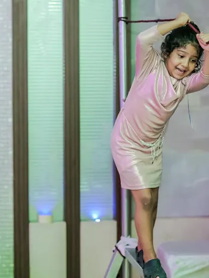 A young girl tackles a rope climbing challenge. Our adventure zones are designed to be both fun and safe, with soft landings and sturdy equipment.