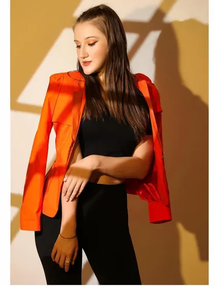 Playing with shadows and light, this portrait uses a gobo to cast a window-like pattern on the model. The bright orange jacket provides a beautiful pop of color.
