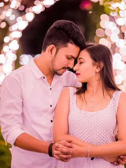 An intimate forehead touch, beautifully framed by an arch of warm lights. This pose is perfect for capturing the quiet connection and trust between a couple.