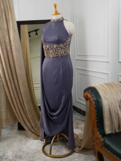 This dusky purple one-shoulder gown is the embodiment of quiet opulence, with its intricately detailed corseted waist and gracefully draped skirt.