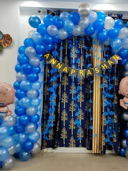 A balloon decoration for an Annaprashan ceremony (first rice-eating ceremony). The setup includes a blue and silver balloon arch with baby-themed foil balloons.