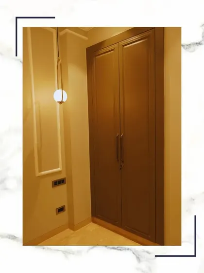 Where elegance meets illumination. This minimalist wardrobe is complemented by a modern pendant light and clean wall moulding, creating a space that dazzles in its simplicity.