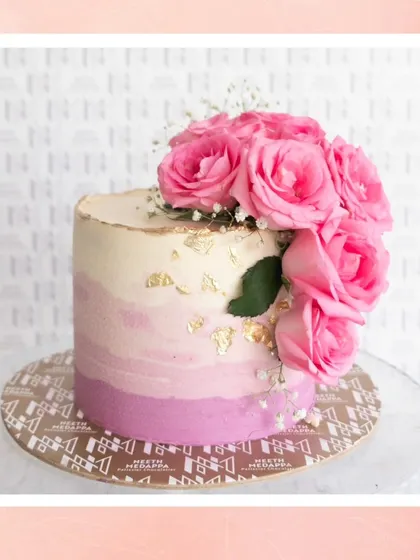 A lovely pink ombre cake adorned with a cascade of fresh pink roses and a touch of gold leaf.