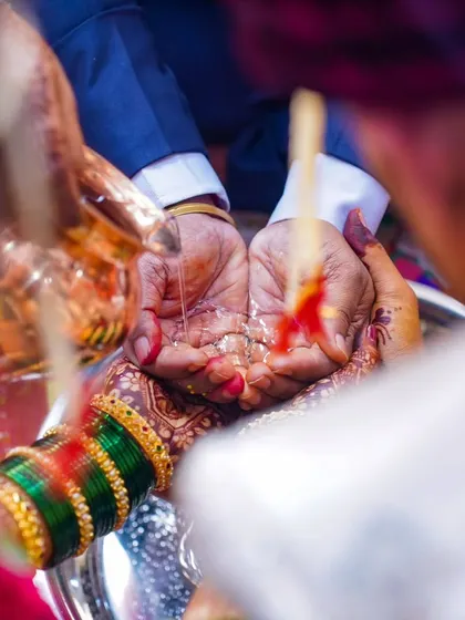 The Kanyadaan ceremony, a poignant moment where the bride's parents give her away. The shot focuses on the hands and the flow of holy water, symbolizing the sacred offering.