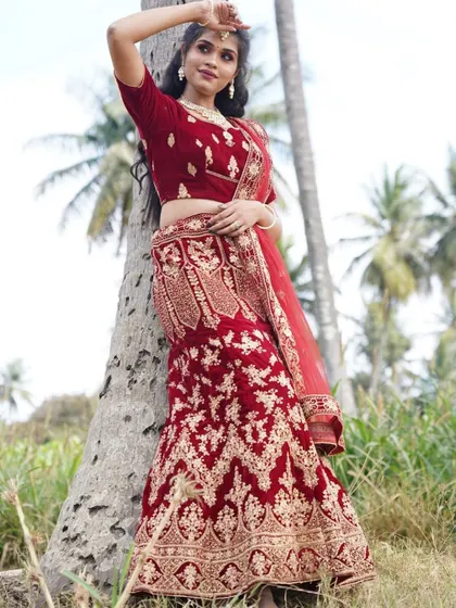 Here is another one of my popular bridal lehenga rentals. This is a deep red velvet lehenga with intricate all-over gold embroidery, shown here in an outdoor photoshoot setting.