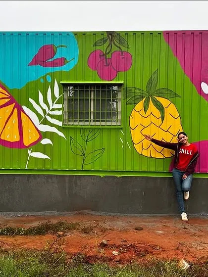 Me leaning against the finished container mural. The design is filled with colorful fruits and vegetables, perfect for a supermarket.
