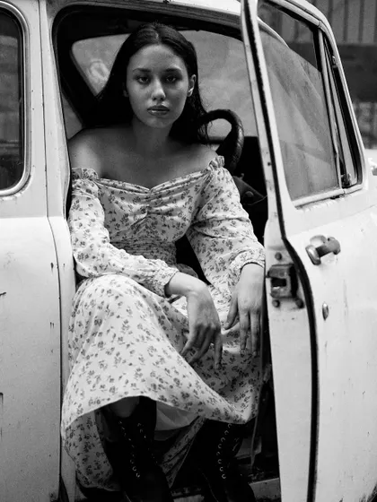Using a vintage car as a prop, this black and white portrait has a timeless, cinematic quality. The contrast between the delicate floral dress and the rustic car tells a story.