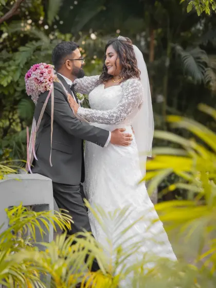 A romantic portrait of the newlyweds in a lush garden setting. The vibrant greenery provides a beautiful contrast to the bride's white gown.