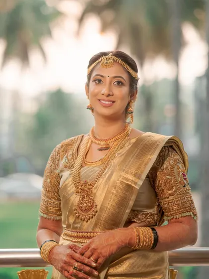 A timeless and elegant bridal portrait. Her makeup is classic and understated, perfectly complementing her gold Kanjivaram saree and traditional jewelry.
