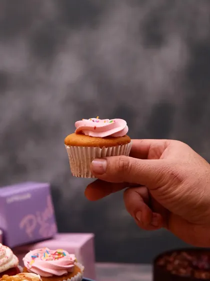 We believe in picking only the best for you. Here's a look at one of our simple yet delicious pink-frosted cupcakes, held up to show its perfect size for a single treat.