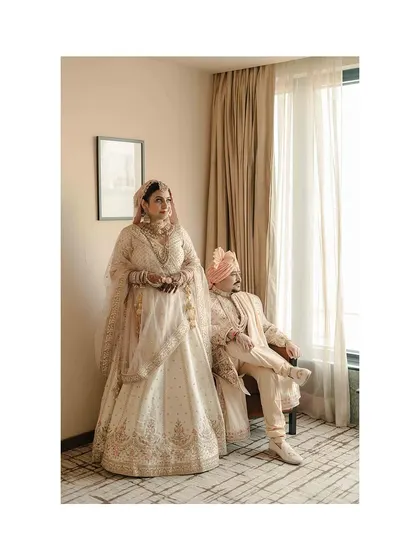 A stylish, full-length portrait of the couple, showcasing their elegant wedding attire and confident poses.
