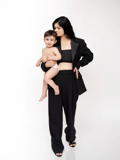 A mother's embrace. This stylish portrait of a mom in a black pantsuit holding her baby close is a modern and powerful take on motherhood photography.